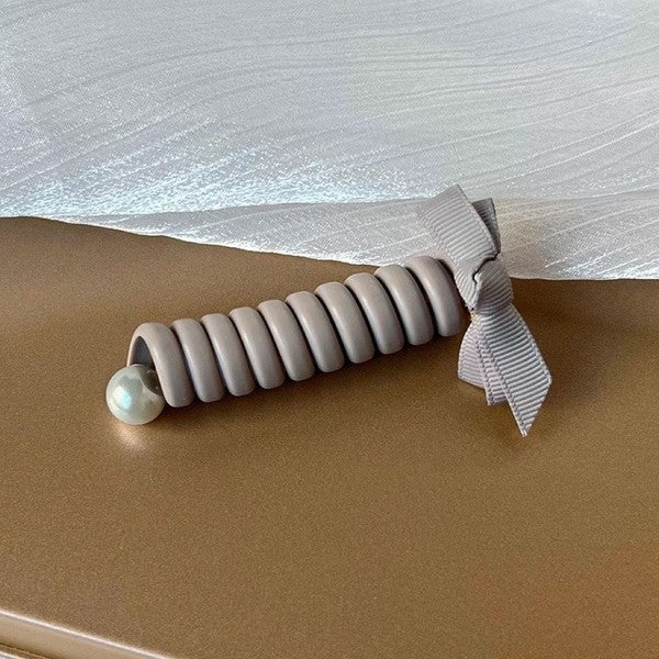 Gray textured roller with a pearl on a beige surface