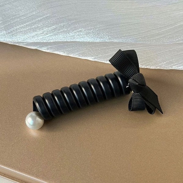 Black textured roller with a pearl on a beige surface