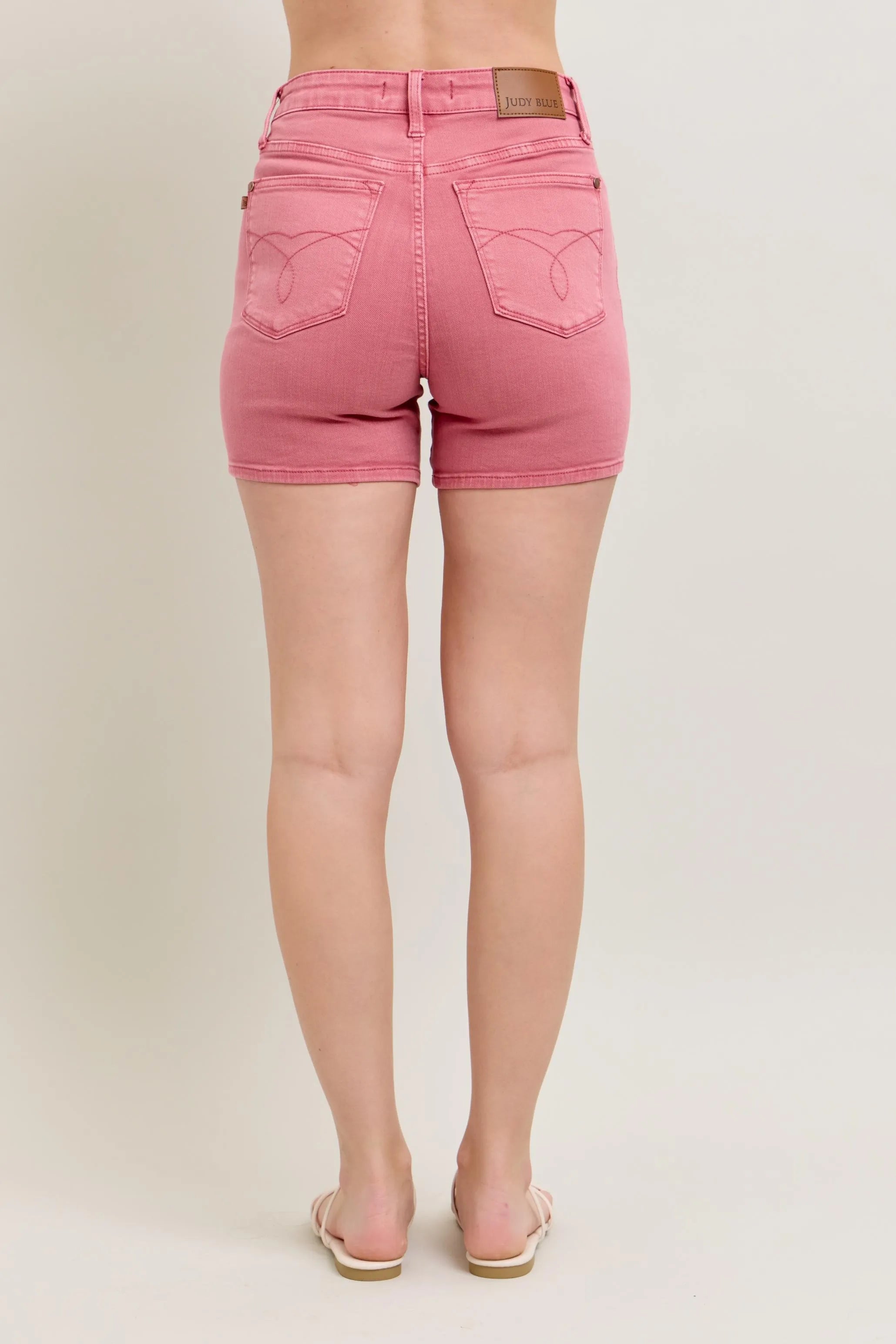 Pink denim shorts worn by a person on a beige background