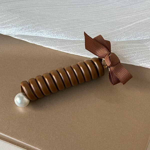 Brown hair tie with a pearl on a beige surface