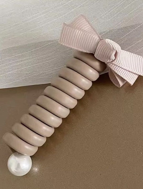 Beige hair tie with a bow on a neutral background