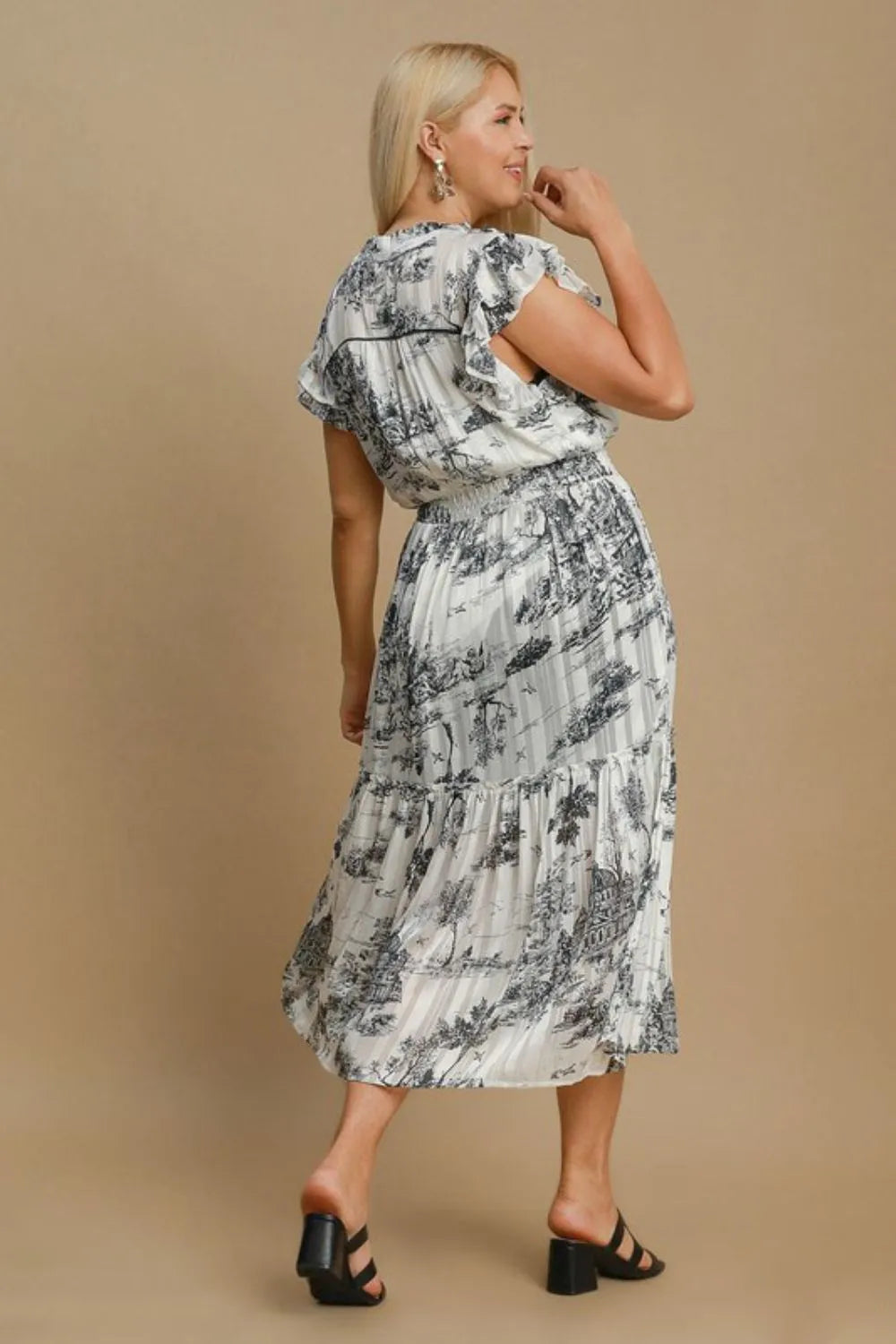 Curvy woman wearing lined flowy midi dress with scenic pattern